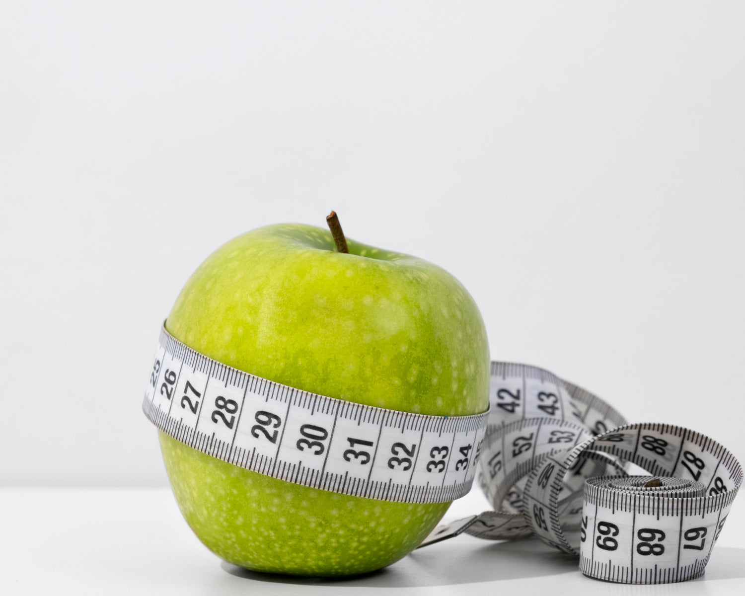 Cinta métrica y manzana representando el control de peso en la menopausia